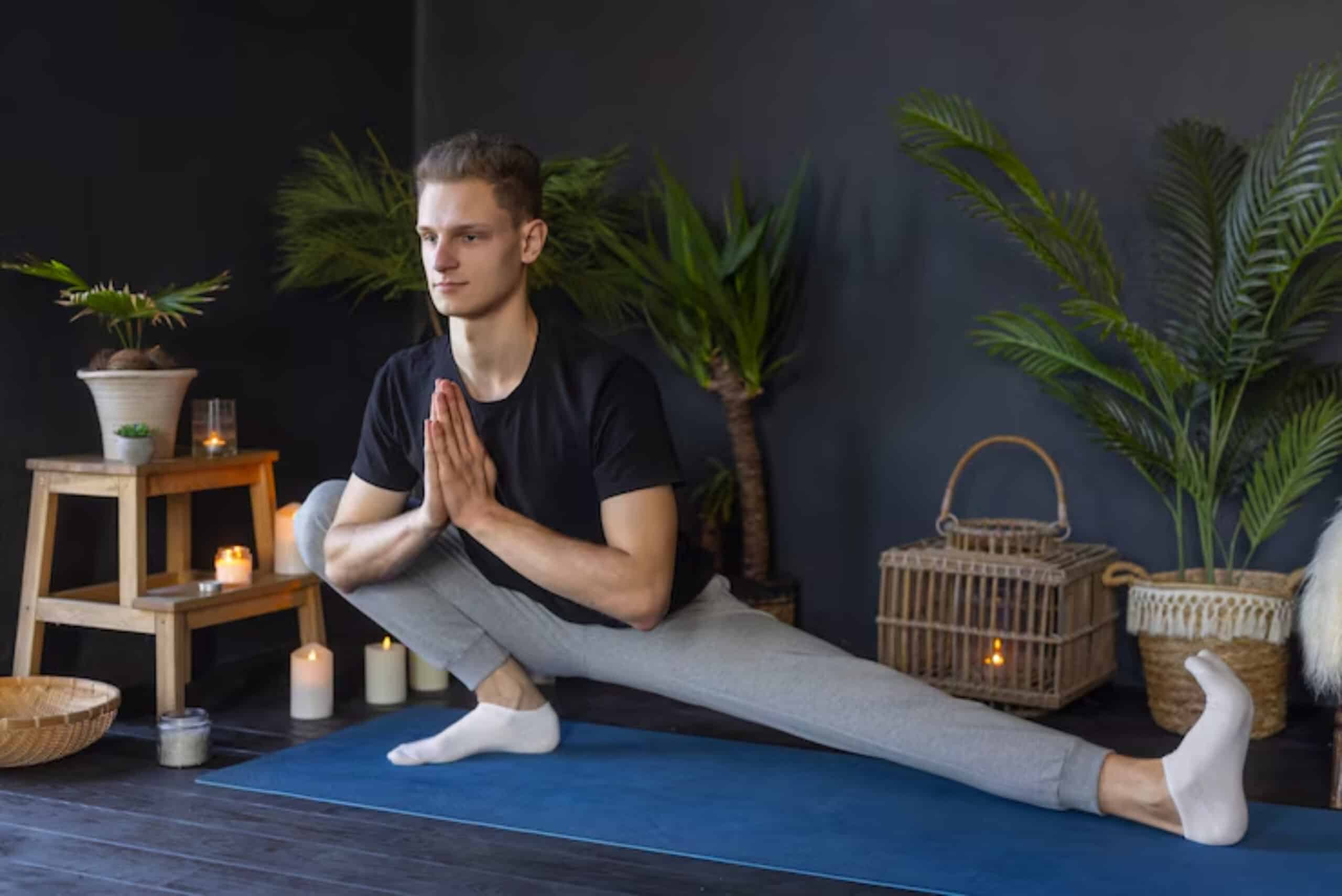 A person in a yoga pose on a blue mat surrounded by plants, candles, and decorative baskets in a serene indoor setting.