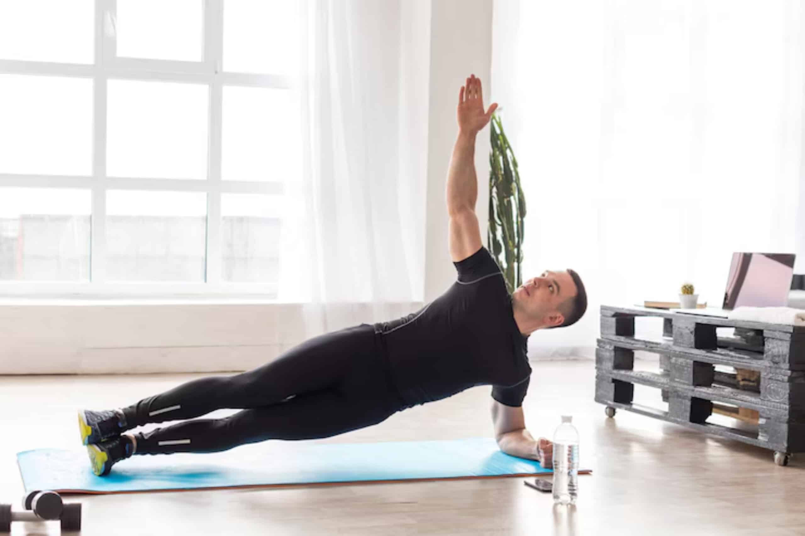 A person performs a side plank exercise on a yoga mat in a bright room with large windows and minimal decor.