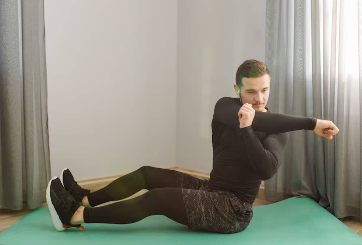A person in athletic wear performs an exercise on a green mat, surrounded by soft natural light and gray curtains. 